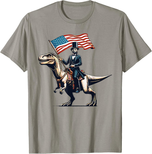Abe Lincoln Riding T-Rex Dinosaur 4th Of July USA Flag Funny T-Shirt - T-Shirt | Sand